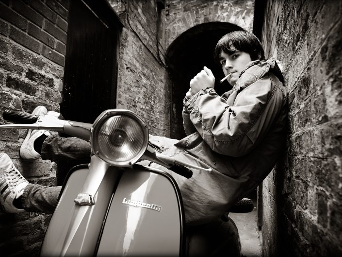 Male biker on a Lambretta in a dark alleyway. PR photography for Quadrophenia production in Hull, East Yorkshire.