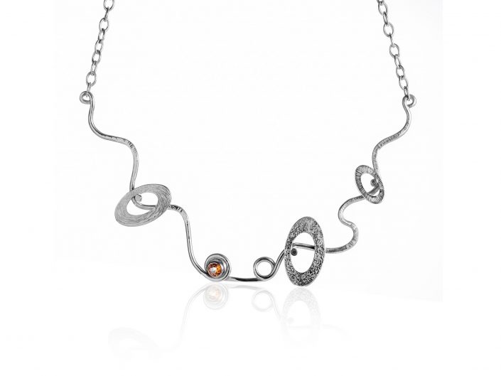 Jewellery photograph of a Silver Necklace with Multi-Stone settings on a white background.