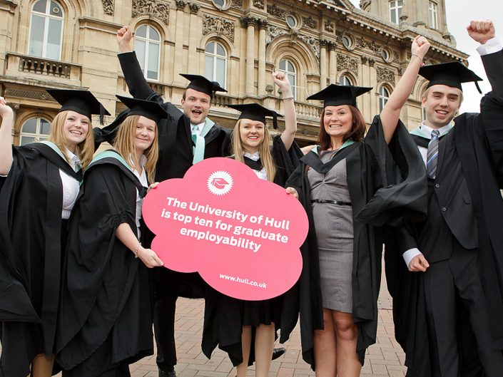 Press photograph of a goup of male and female Hull University graduates celebrating top ten employability Hull City Centre.