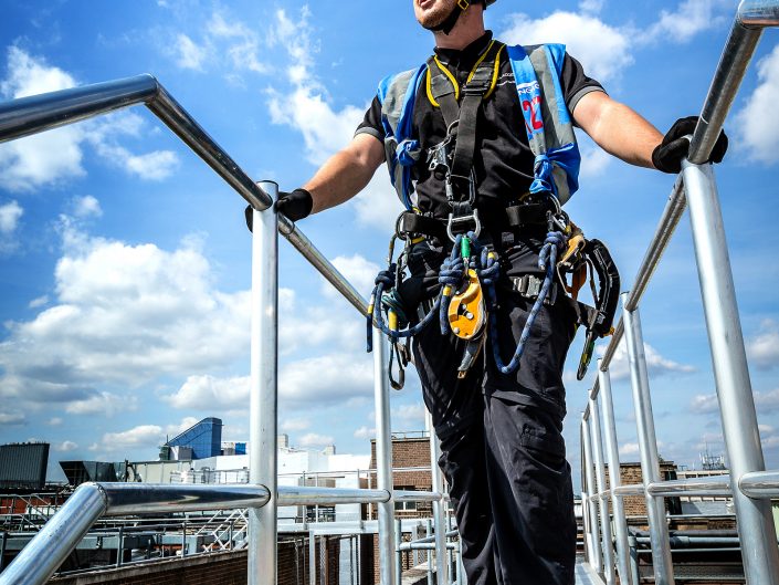 Construction worker wearing a safety harness on a roof gangway in Birmingham.