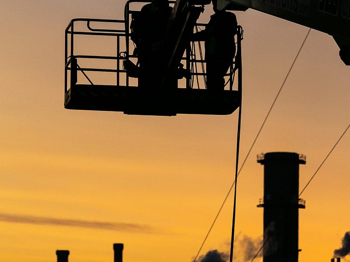 Sunset photograph of workers operating a industrial cherry picker on a construction site in Lincolnshire.