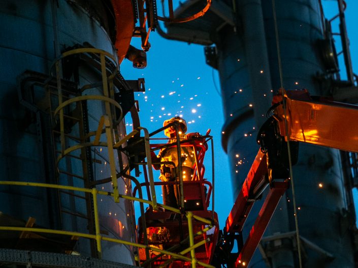 Worker in an industrial location producing sparks.