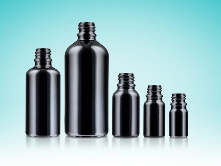 Black Glass Bottles on a blue background photographed in a Hull, Products and packaging photography studio.