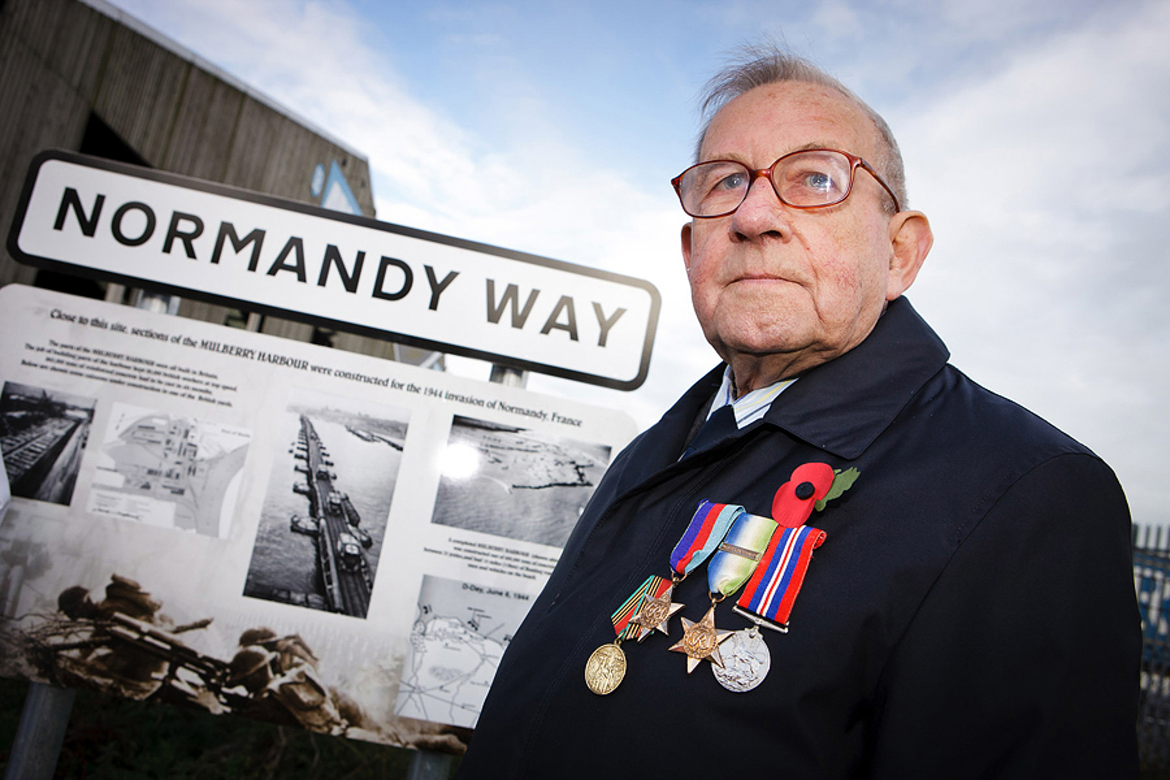 News photography of a war veteran alonside the Normandy Way road sign in Goole, East Yorkshire.