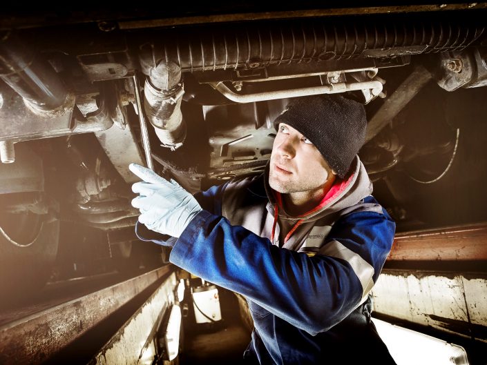 Mechanic working on a truck within an industrial environment.